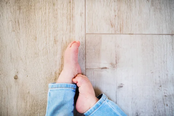 Un pie de bebé de un niño irreconocible sentado en el suelo en casa. Copiar espacio . —  Fotos de Stock