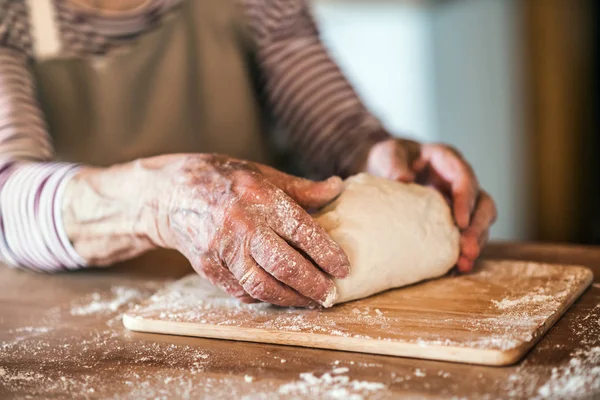 An unrecognizale senior woman kneading dough in the kitchen at home. — Stock Photo, Image