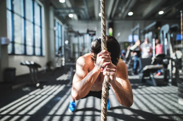 Ajuste joven en el gimnasio haciendo ejercicio con cuerda de escalada . — Foto de Stock