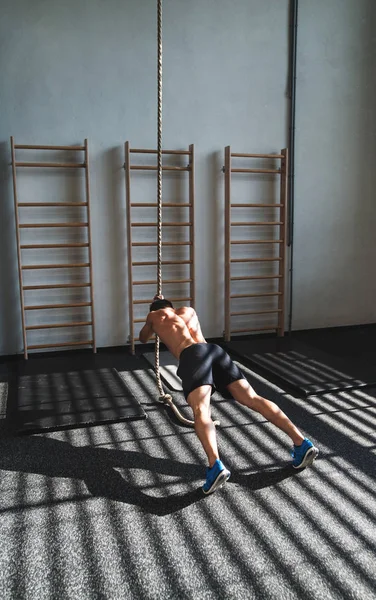 Passar ung man i gymmet träna med klättring rep. — Stockfoto