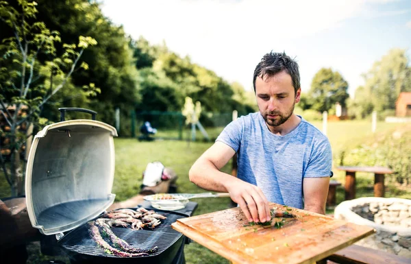 Olgun adam da arka bahçede barbekü ızgara deniz ürünleri yemek. — Stok fotoğraf
