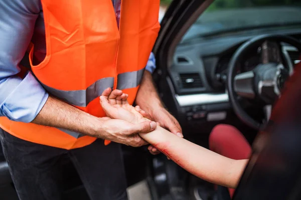 Un uomo irriconoscibile che controlla il polso di una guidatrice dopo un incidente d'auto . — Foto Stock