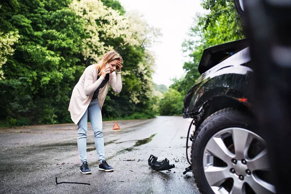 Telefon görüşmesi genç kadın bir araba kazasında sonra hasarlı araç tarafından. — Stok fotoğraf