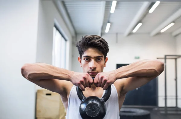 Ung träna spansktalande mannen i gymmet lyft kettlebell. — Stockfoto