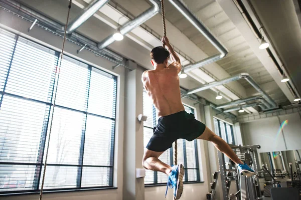 Pria muda telanjang dada di gym memanjat tali . — Stok Foto