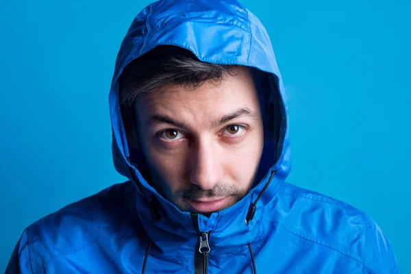 Porträtt av en ung man i en studio med anorak på en blå bakgrund. — Stockfoto