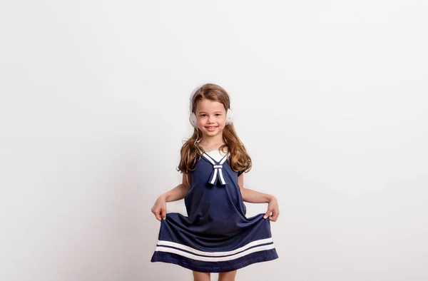 Retrato de uma menina pequena com fones de ouvido em estúdio em um fundo branco . — Fotografia de Stock