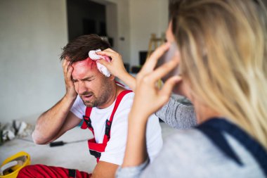 Smartphone inşaat sahasında bir kazadan sonra adam işçi yardımcı olan bir kadın.