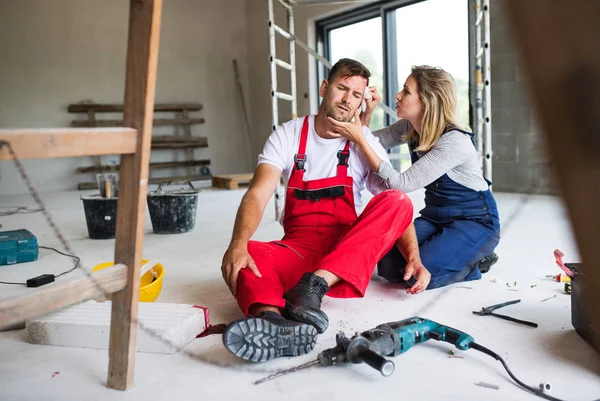 A woman helping man worker after an accident at the construction site. — Stock Photo, Image