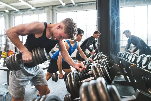 Jonge past mannen in sportschool trainen met halters. — Stockfoto