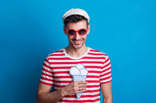 Portret van een jonge man in een studio met zonnebril op een blauwe achtergrond. — Stockfoto