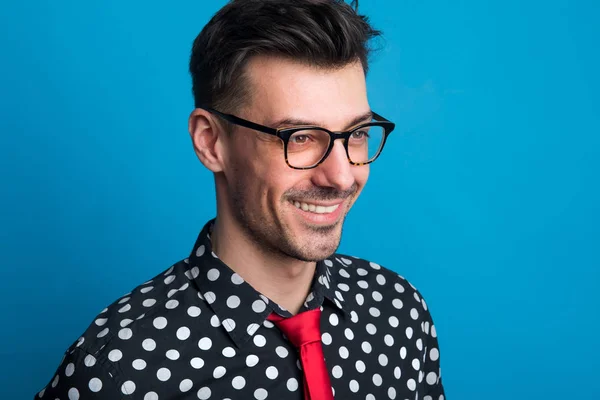 Retrato de um jovem com óculos em um estúdio em um fundo azul . — Fotografia de Stock