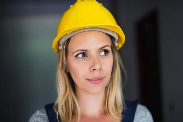 Jonge vrouw werknemer met een gele helm op de bouwplaats. — Stockfoto
