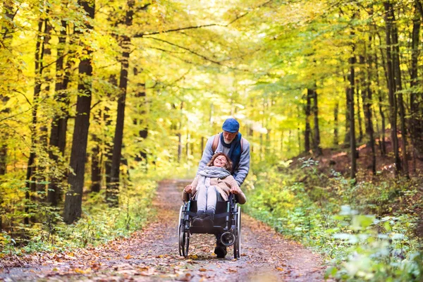 Coppia anziana con sedia a rotelle nella foresta autunnale . — Foto Stock