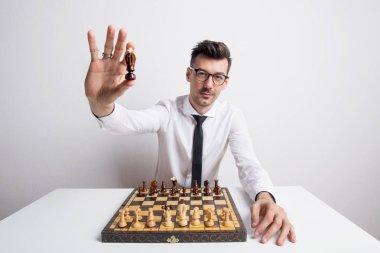 Bir stüdyoda satranç oynamayı ve bir kral tutan genç bir adam portresi chessman.