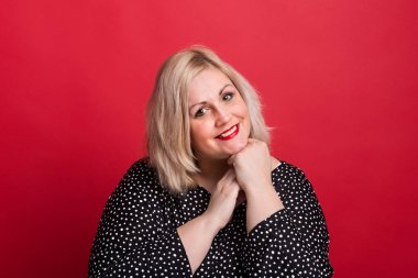 Studio kırmızı bir arka plan üzerinde mutlu bir çekici kilolu kadın.