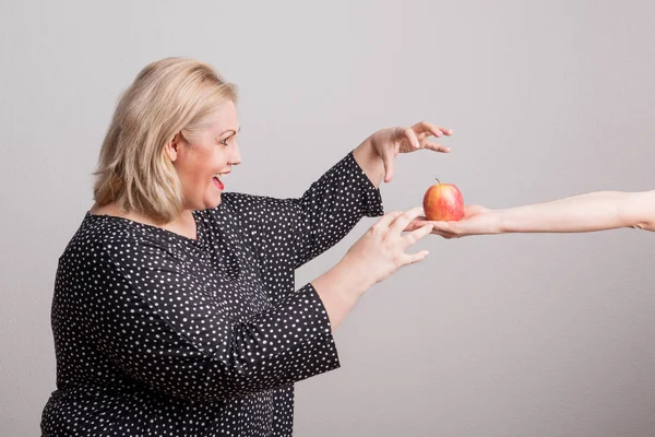 Çekici bir kilolu kadın Studio bir elma veren bir el. — Stok fotoğraf