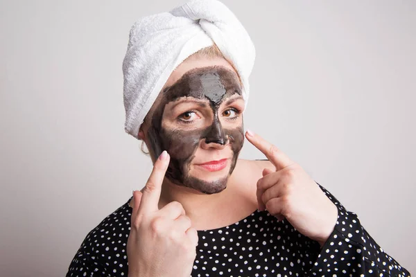 Seorang wanita kelebihan berat badan menarik dengan masker wajah hitam di wajahnya di studio . — Stok Foto