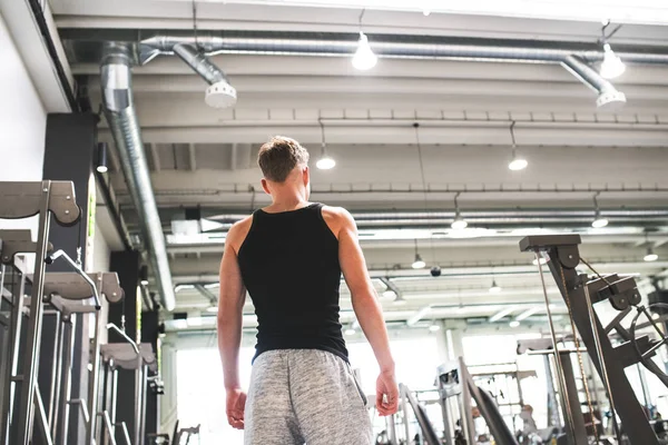 Joven en el moderno gimnasio crossfit, de pie. Vista trasera . — Foto de Stock