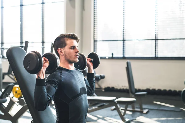 Jeune homme en forme dans la salle de gym exercice avec haltères. Espace de copie . — Photo