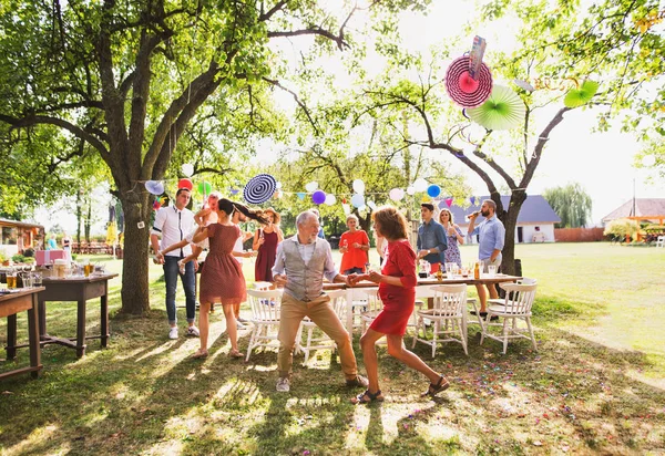 Un couple de personnes âgées et une famille dansant sur une garden party à l'extérieur dans la cour . — Photo