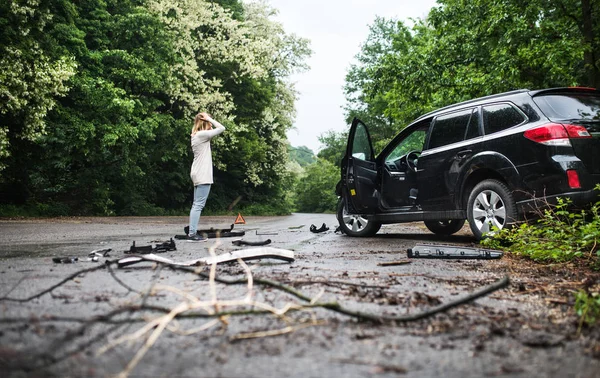 Молода жінка стоїть біля пошкодженого автомобіля після ДТП . — стокове фото