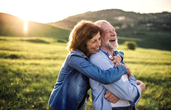 Side view of senior couple hugging outside in spring nature at sunset. — Stock Photo, Image