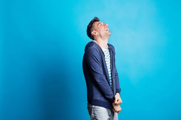 Portret van een jonge gelukkig man in een studio op een blauwe achtergrond. — Stockfoto