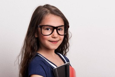 Gözlük ve bir stüdyoda ayakta, Not defteri tutan üniforma ile küçük bir kız öğrenci.