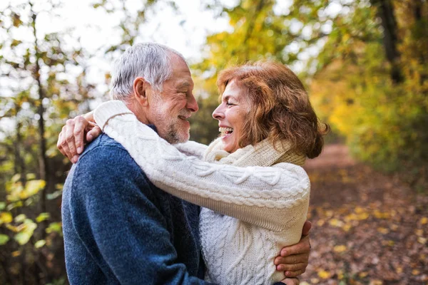 Seniorpaar blickt sich herbstlich an und umarmt sich. — Stockfoto