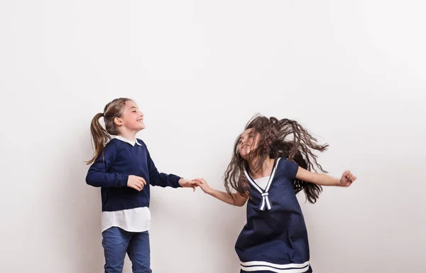 Duas meninas pequenas em um estúdio, de mãos dadas, se divertindo . — Fotografia de Stock