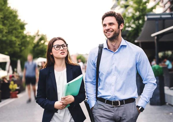 A young businessman and businesswoman walking on a sidewalk. — Stock Photo, Image