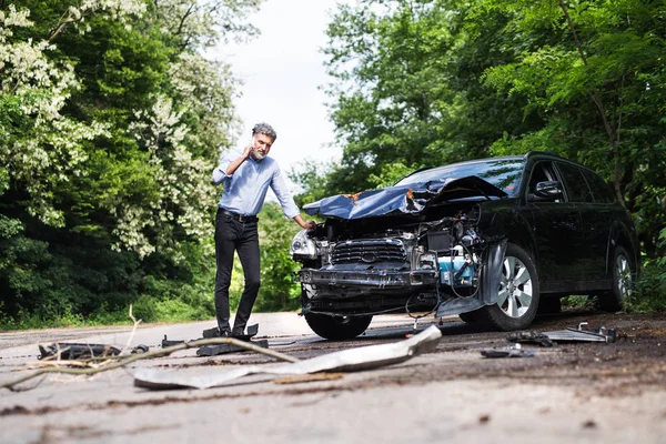 Пожилой человек, стоящий у машины, делает телефонный звонок после аварии . — стоковое фото