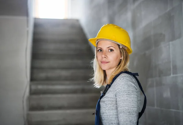 Jonge vrouw werknemer met een gele helm op de bouwplaats. — Stockfoto