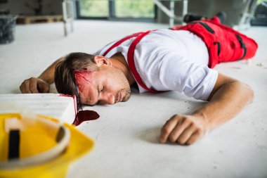 İnşaat alanı üzerinde kazadan sonra yerde yatarken bir bilinçsiz adam işçi.