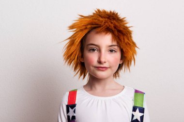 Küçük bir kız bir peruk ve bir stüdyoda bir palyaço kostüm.