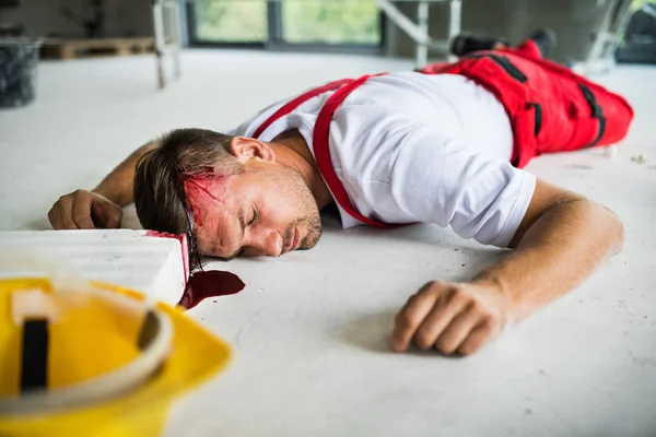 En medvetslös man arbetare liggande på golvet efter olycka på byggarbetsplatsen. — Stockfoto