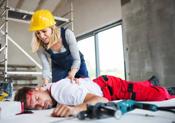 A woman found man worker lying unconscious on the floor at the construction site. — Stock Photo, Image