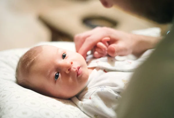 Newborn baby lying on bed, unrecognizable father stroking her head. — Stock Photo, Image