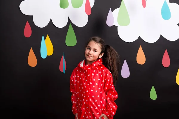 Uma menina pequena em um fundo preto com nuvens e gotas de chuva . — Fotografia de Stock