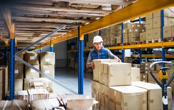 Hombre mayor trabajador de almacén descargando cajas de una transpaleta . — Foto de Stock