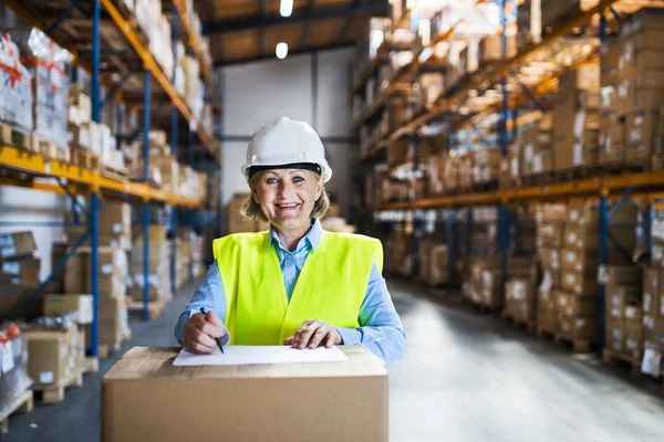 A senior woman warehouse worker or supervisor controlling stock. — Stock Photo, Image