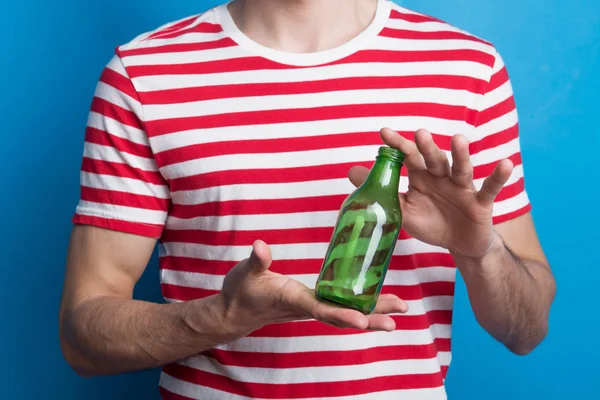 Een close-up van een onherkenbaar man in een studio met een lege fles. — Stockfoto