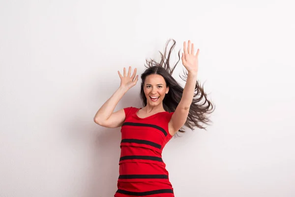 A young beautiful delighted woman with black and red t-shirt in a studio.