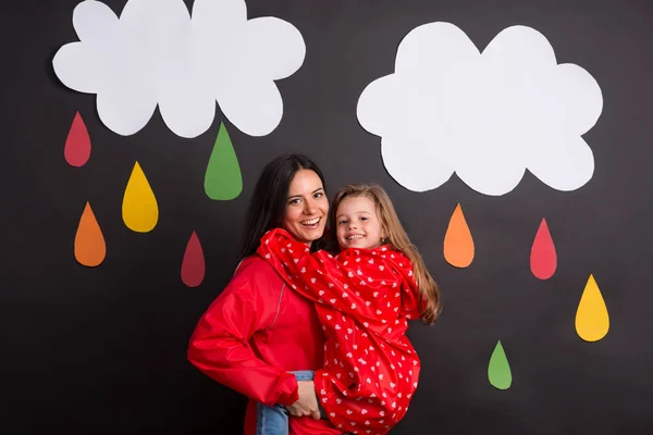 A small girl with her mother on a black background with clouds and raindrops. — Stock Photo, Image