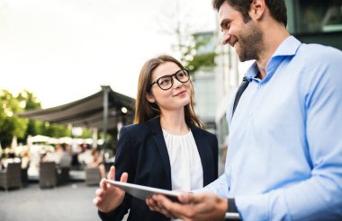 Açık havada bir genç işadamı ve işkadını kullanarak tablet.