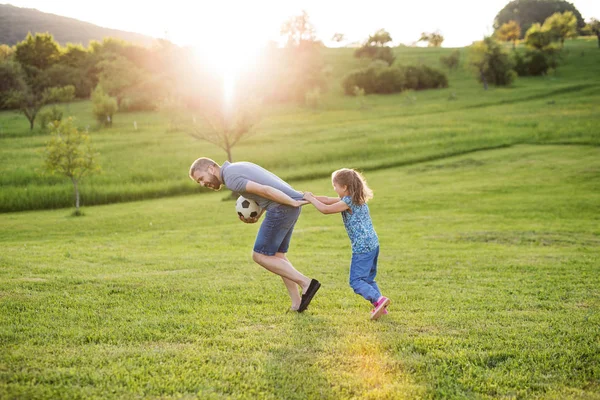 Father with a small daughter playing with a ball in spring nature at sunset. — Stock Photo, Image