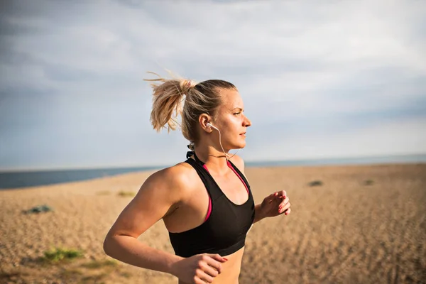 Joven corredora deportiva corriendo afuera en una playa en la naturaleza . — Foto de Stock