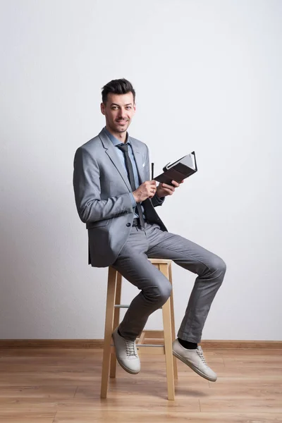 Portrait d'un jeune homme réfléchi avec un stylo et un journal intime dans un studio, la planification . — Photo