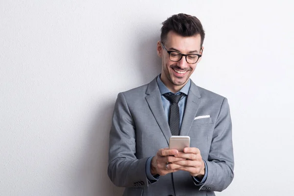 Portrait of a young man with smartphone in a studio, text messaging. — Stock Photo, Image